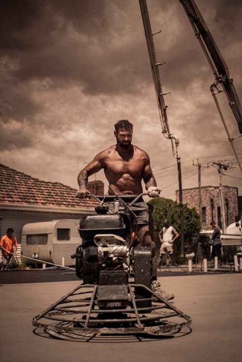 Concrete worker operating power trowel on construction site